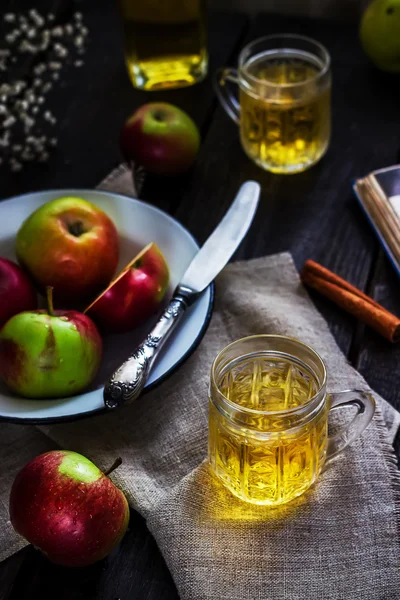 Jablečný mošt a jablka na bílé desce. Tmavý dřevěný stůl. — Stock fotografie