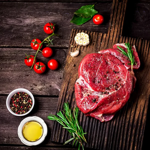  Doğrama tahtası, domates, otlar ve baharatlar koyu ahşap masa üzerinde sığır eti.