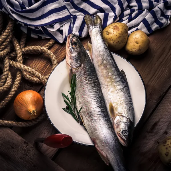 Patates, soğan, baharat ve otlar ahşap bir masa üzerinde ham nehir balığı. — Stok fotoğraf