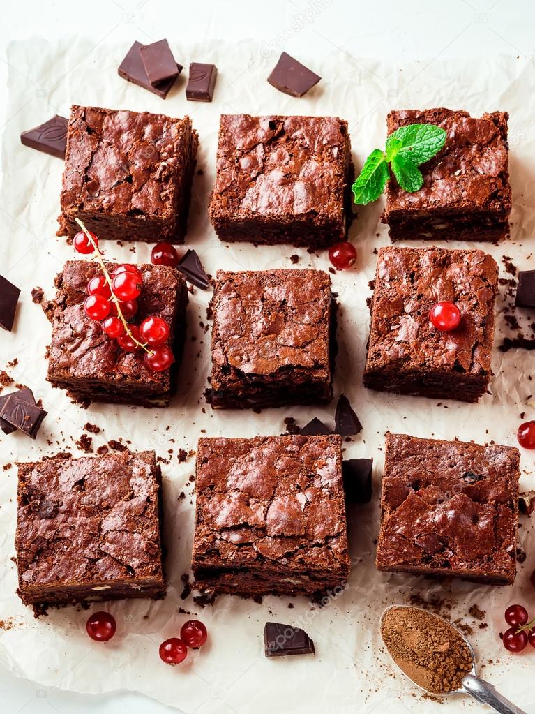  Brownie pieces with nuts decorated with berries and mint leaves on the white paper.