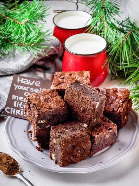 Brownie pieces with nuts on the plate and two cups of milk. — Stock Photo, Image