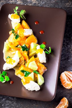 Keçi peyniri ve mandalina kahverengi plaka üzerinde salatası. 