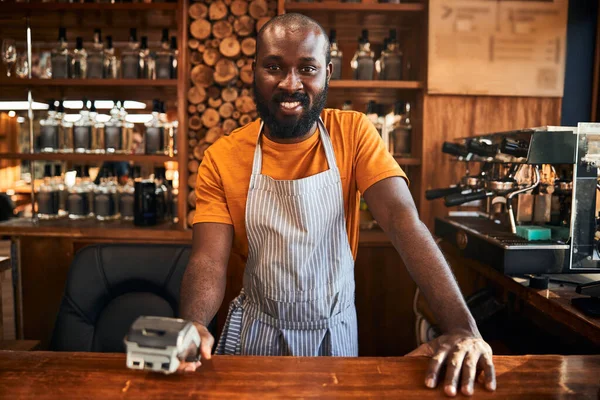 Vrolijke mannelijke barman holding terminal voor contactloze betaling — Stockfoto