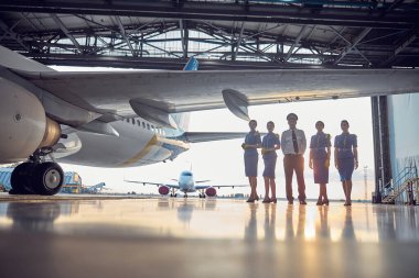Hangarda üniformalı havacılık ekibiyle uçağın bir parçası.