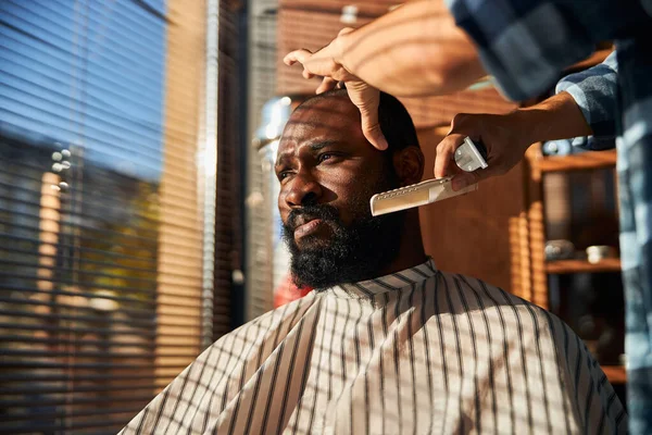 Чоловічий перукар розчісує клієнтську бороду в перукарні — стокове фото