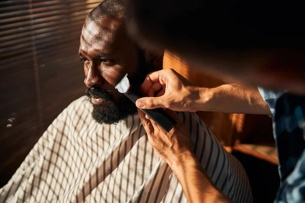 Перукарська гоління клієнтська борода з електричним тримером в перукарні — стокове фото