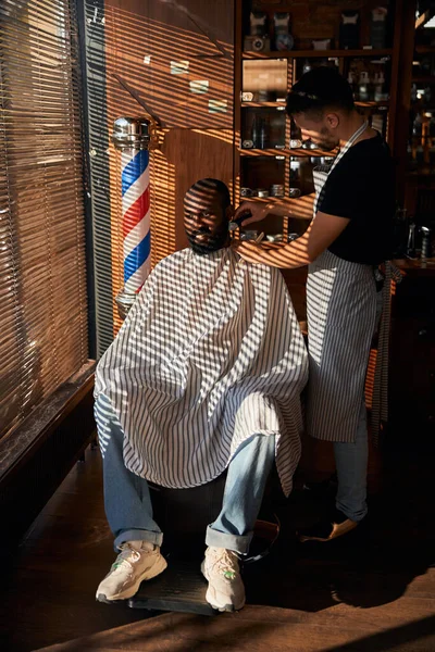 Barbier dans le tablier rasage barbe client dans le salon de coiffure — Photo