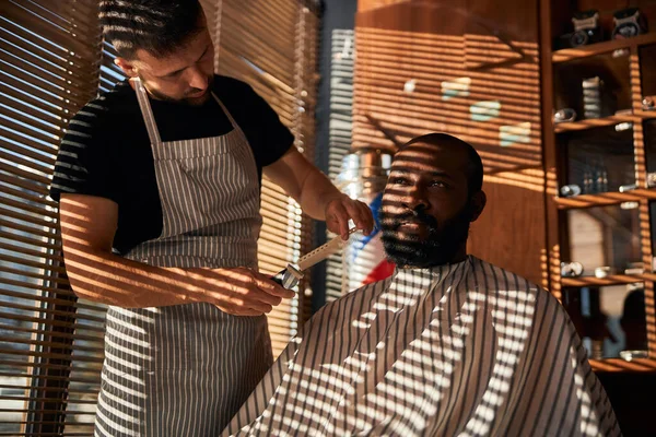 Чоловічий перукар в обрізанні фартуха клієнтська борода в перукарні — стокове фото