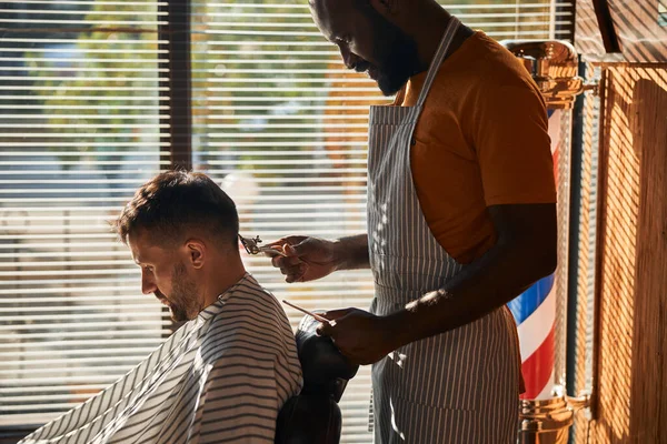 Snygg man frisör klienthår med metall hårklippare — Stockfoto