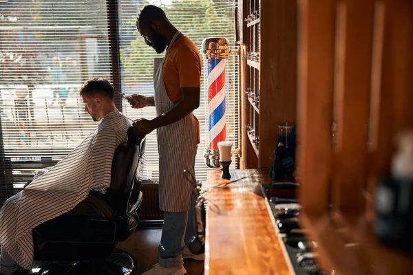 Barbudo barbeiro masculino corte de cabelo do cliente com cortador de cabelo de metal — Fotografia de Stock