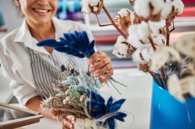 Güzel bayan çiçekçi. Kuru mavi çiçeklerle poz veriyor.