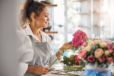 Çekici kadın çiçekçi güzel pembe çiçeğe bakıyor.