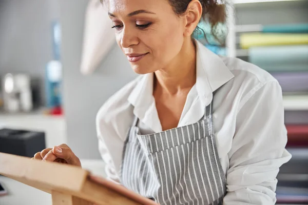 Gladsome vrouwelijke winkelassistent kijkt naar de tablet — Stockfoto