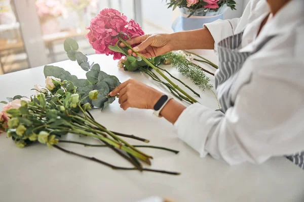 Manos cuidadosas de un florista que arregla las flores en una composición — Foto de Stock