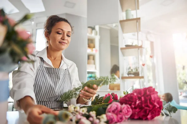 Geconcentreerde vrouwelijke bloemist kiezen bloemen voor bloemcreaties — Stockfoto