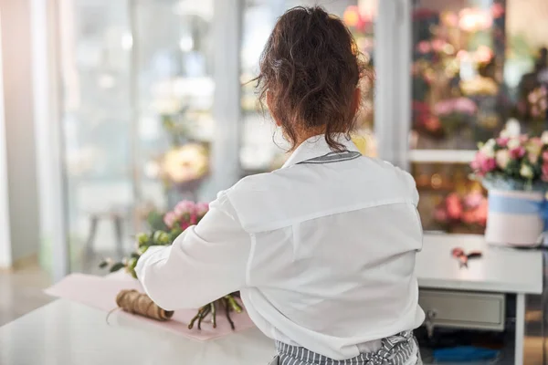 Jovem mulher trabalhando em fazer um buquê em seu estúdio de flores — Fotografia de Stock