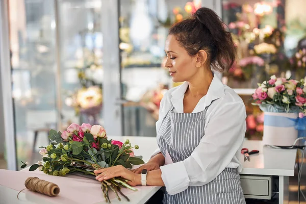 Senhora bonita organizando flores em um buquê agradável — Fotografia de Stock