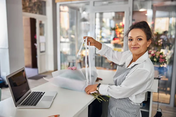 Energetische brunette bloem winkel werknemer het maken van een boeket — Stockfoto