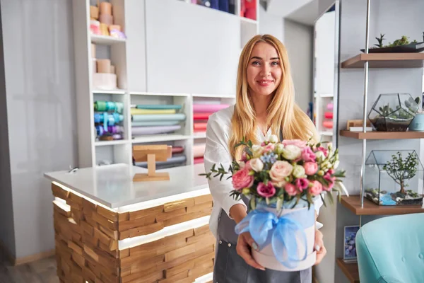 Senhora florista alegre segurando um monte de flores na caixa — Fotografia de Stock