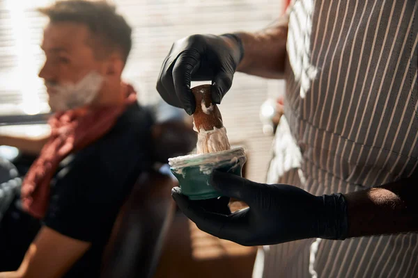 Чоловічий перукар обгортає вершки для гоління пензлем — стокове фото