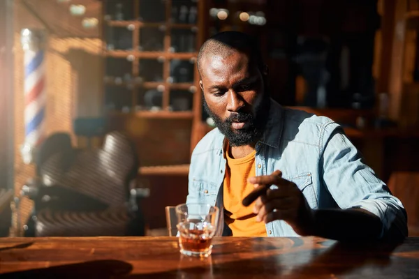 Hombre afroamericano guapo fumando cigarro en el bar de la barbería — Foto de Stock