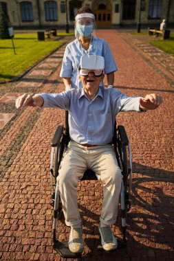 Yaşlanan adam huzurevinin önünde sanal gerçeklik gözlüğü kullanıyor.