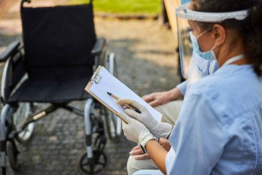 Dosyaları gösteren maskeli ve koruyucu başlıklı doktor.