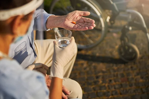 Wrinkled hand holding an antibiotic on a sunny day — Stock Photo, Image