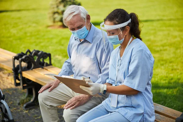 Doktor ukazující poznámky na složce se starým pacientem — Stock fotografie