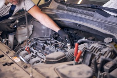Benzin istasyonunda oto tamirci araba motoru tamir ediyor.