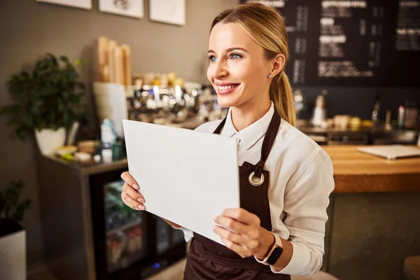 Gelukkig koffiehuis ober in schorten met wit papier in de hand — Stockfoto