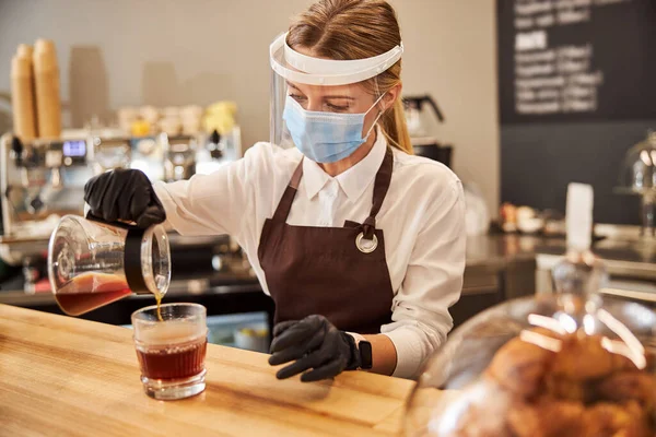 Blond, sjarmerende kvinne i beskyttende medisinmaske som jobber på kaffebar – stockfoto