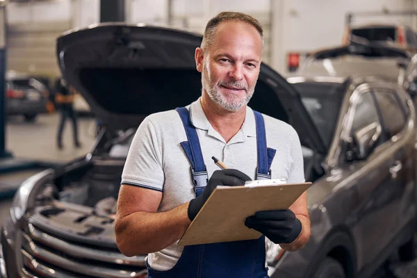 Automechaniker schreibt an Klemmbrett an Tankstelle — Stockfoto