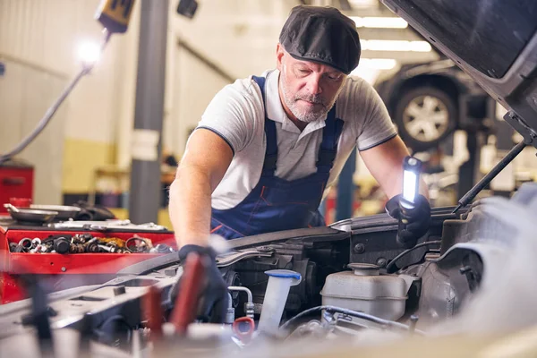 Bärtiger Automechaniker mit Mütze arbeitet in der Autoreparaturwerkstatt — Stockfoto