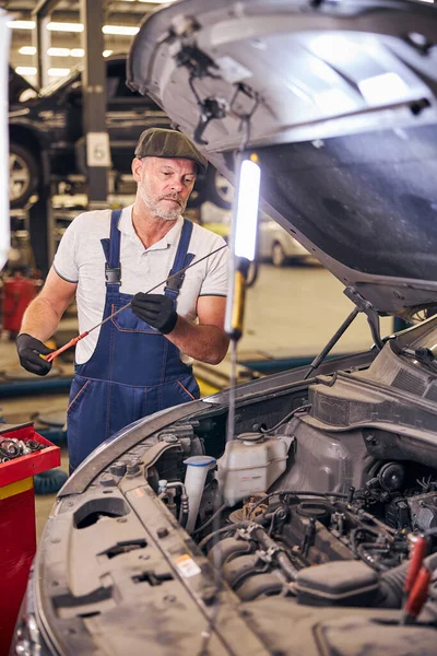 Schwerbärtiger Mann arbeitet an Auto-Reparatur-Tankstelle — Stockfoto