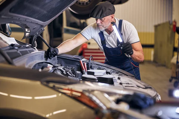 Vousatý auto automechanik opravy auto na čerpací stanici — Stock fotografie