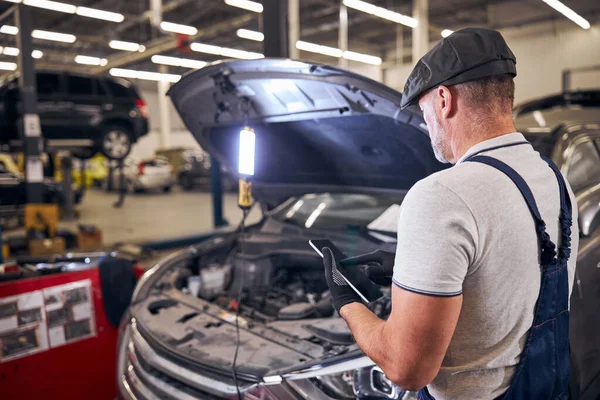 Automechanik používající tablet na autoopravně — Stock fotografie