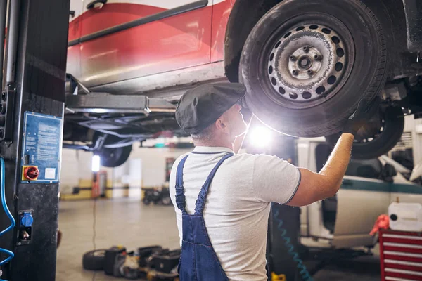 Male technician repairing car at repair service station