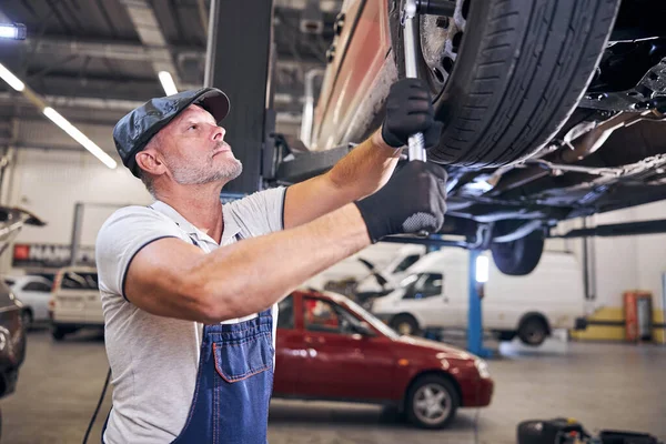 Bärtiger Mechaniker repariert Autorad an Auto-Tankstelle — Stockfoto