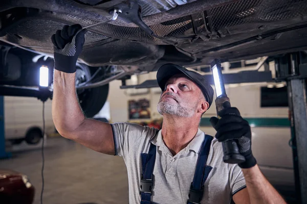 Handsome male worker repairing car in auto repair shop — Stock Photo, Image