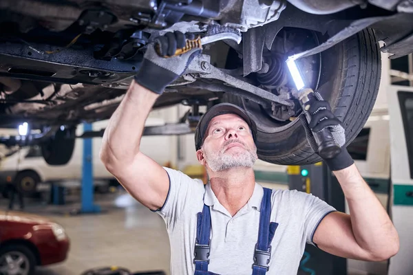 Seriöser männlicher Mechaniker repariert Auto an Auto-Tankstelle — Stockfoto