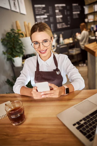 Verkoopster poseert bij het houten bureau in de winkel — Stockfoto