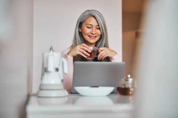 Весела жінка використовує сучасний ноутбук вдома — стокове фото