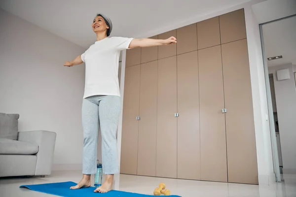 Mujer encantadora en ropa deportiva haciendo elementos en la práctica de yoga en casa — Foto de Stock