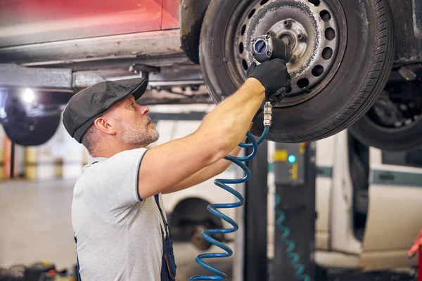 Baard auto monteur reparatie auto wiel schijf in de garage — Stockfoto