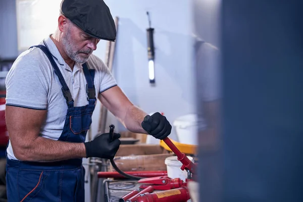 Baard mannelijke monteur in cap werken in de garage — Stockfoto