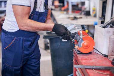 Garajda öğütme makinesi kullanan erkek işçi.