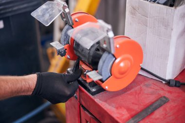 Tamirci oto tamirhanesinde öğütme makinesi kullanıyor.