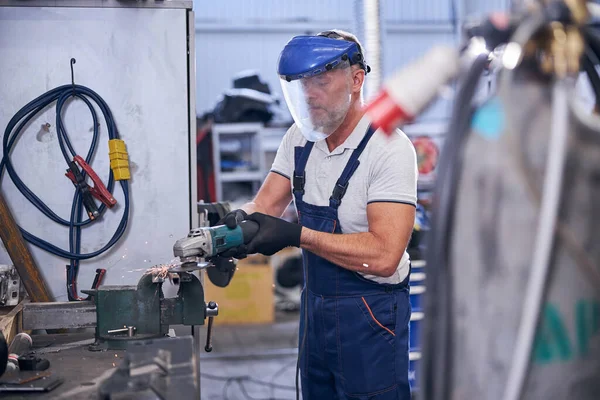 Baard monteur in beschermende masker met behulp van slijper in de garage — Stockfoto