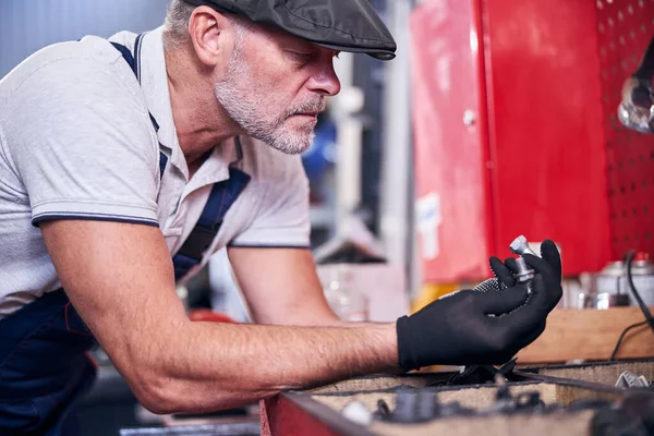 Γενειοφόρος μηχανικός σε γάντια που κρατούν ασημένια μπουλόνια — Φωτογραφία Αρχείου